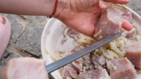 Hands threading marinated meat onto metal skewers for barbecue Stockbeeldmateriaal 340964942