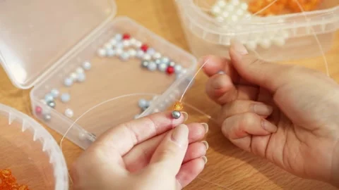 Hands threading pearl and metallic beads on string for delicate beadwork cr.. Stock Footage 339567667