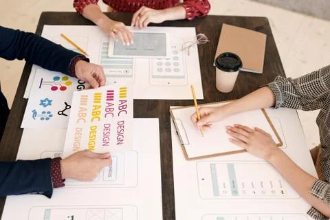 Hands of three creative mobile application developers working by wooden table Stock Photos
