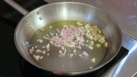 Hands throwing cut onion and garlic into the hot frying pan with oil Stock Footage 104331893