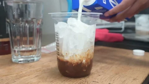 Hands throwing milk into a coffee cup Stock Footage 236904251