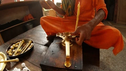 Hands tie big cotton wick in ghee to ritual light fixture Indian monk in orange  Stock Footage 100298025
