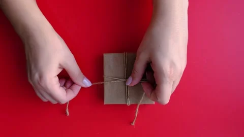 Hands tie a bow on the gift box. layout on a red background. Stock Footage 165833502