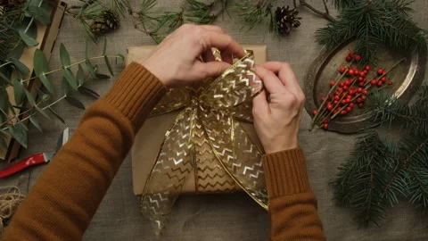 Hands tie a gift wrapping bow. Woman decorating Christmas gift box. Stock Footage 222893674