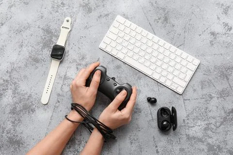 Hands tied with controller cable, gaming addiction concept, digital device de 스톡 사진