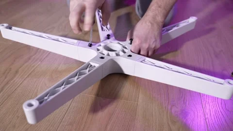 Hands tightening bolts with a screwdriver while assembling an office chair base Stock-Footage 327910028