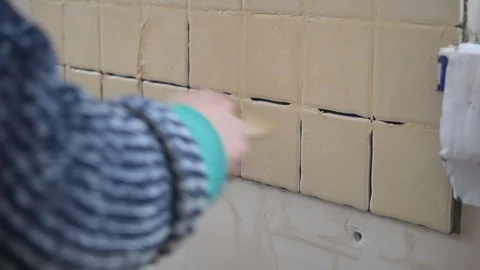 Hands of tile worker filling gaps between tiles with grout Stock Footage 87794788