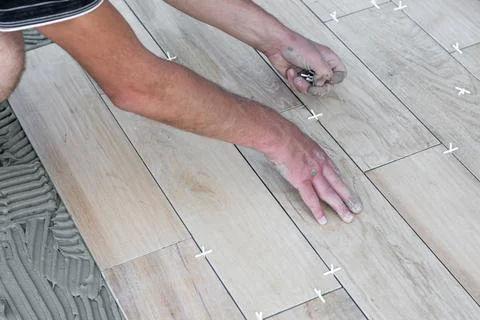 The hands of the tiler lying or installing modern, ceramic tile above cement on 库存照片