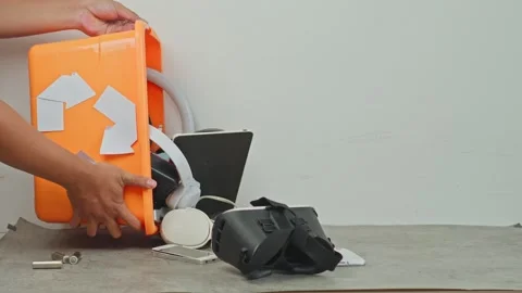 Hands tilting an e-waste recycling box to pour out discarded electronics and Stock-Footage 340576471