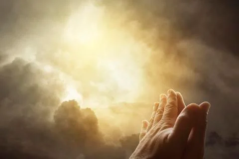 Hands together praying in bright sky Stock Photos