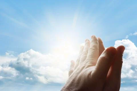Hands together praying in bright sky Stock Photos