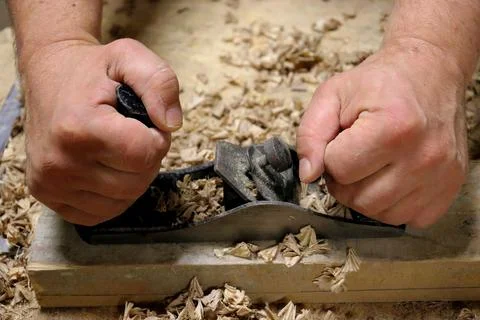 Hands with a tool on the background of a carpentry workshop. Stock Photos
