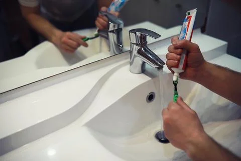 Hands with tooth brush and paste on blurred background in the bathroom in t.. Stock Photos