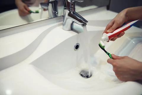 Hands with tooth brush and paste on blurred background in the bathroom in t.. Stock Photos