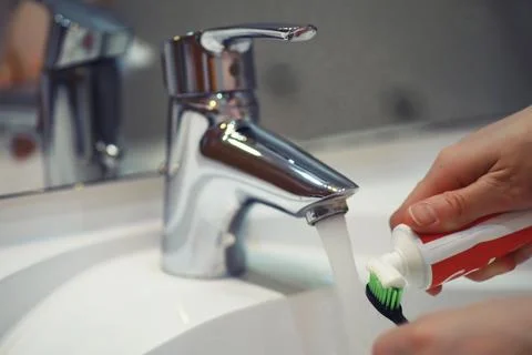 Hands with tooth brush and paste on blurred background in the bathroom in t.. Stock Photos
