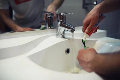 Hands with tooth brush and paste on blurred background in the bathroom in t.. Stock Photos