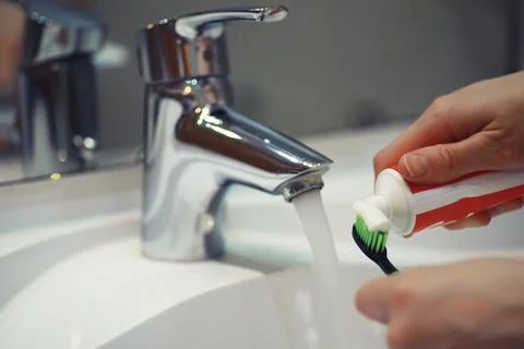 Hands with tooth brush and paste on blurred background in the bathroom in t.. Stock Photos