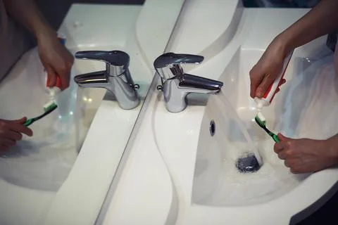 Hands with tooth brush and paste on blurred background in the bathroom in t.. Stock Photos