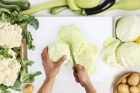 Hands top view cutting cabbage on white chopping board on kitchen topwork wit Stock Photos