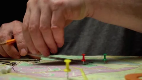 Hands of a topographer using a pencil and compass to place colored push pins on Stock Footage 332866822