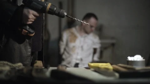 Hands of torturer use drill close to kidnapped tied hostage and intimidating man Stock Footage 86285302