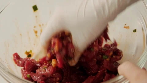 Hands tossing thinly sliced fresh beef in seasoning. The process of making Korea Stock Footage 247231819