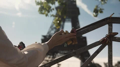 Hands touching love locks on a bridge railing with the Eiffel Tower behind Stock Footage 346386711