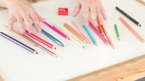 Hands touching scattered colored pencils with sharpener on white table Stock Footage 331514168