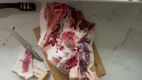 Hands Trim and Portion a Large Piece of Raw Pork on a Cutting Board in a Stock Footage 343250035