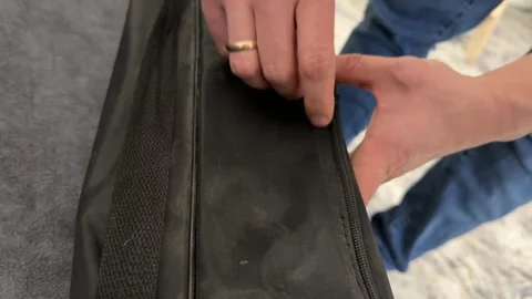 Hands trying to open a black zippered case or bag. Close up of pulling the Video stock 336976709