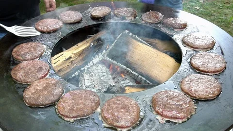 Hands turn baking minced meat pieces for burgers. Slow motion shot Stock Footage 115633663