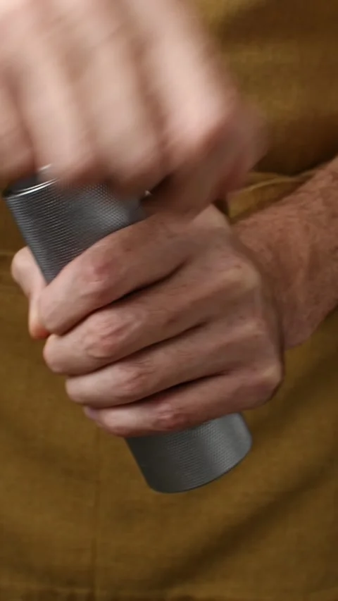 Hands turn the crank of a compact manual coffee grinder in vertical close-up Stock Footage 346743540
