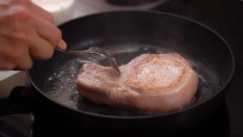 Hands turn over meat steak, meat on bone in a frying pan, frying Stock Footage 232780324