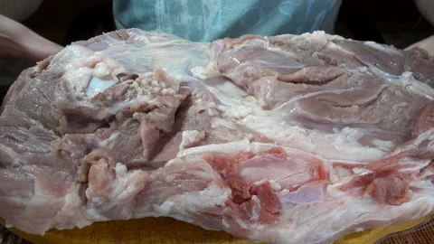 Hands turn over a piece of raw meat on a wooden board in 4K. Stock Footage 129547796