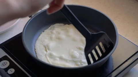 Hands turn the pancake on the pan while cooking pancakes. Stock Footage 112913828