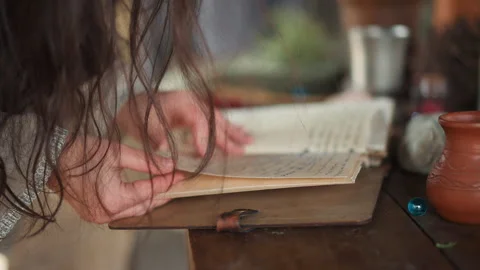 Hands turning aged leather notebook on wooden desk under warm natural light Stock Footage 343686728