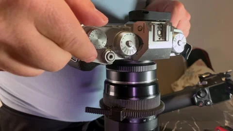 Hands turning camera exposure control knob close-up, adjusting settings on Stockbeeldmateriaal 333649599