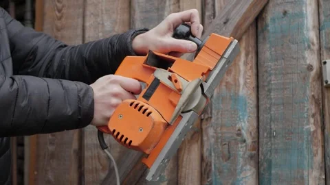 Hands turning on orange electric hand planer Stock Footage 342867917