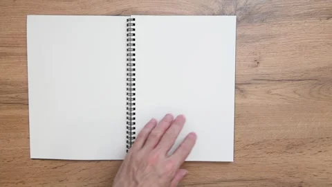 Hands turning pages of a spiral notebook on a wooden table Vídeo Stock 316877946