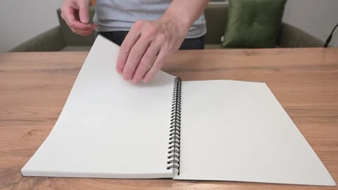 Hands turning pages of a spiral notebook 库存影片 316878018