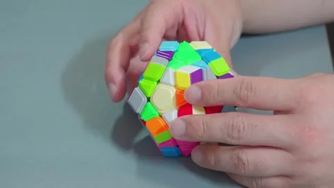 Hands Twisting Megaminx Speedcube On Grey Desk Video stock 339124098