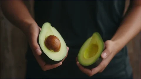 Hands twisting open a fresh ripe avocado in half Stock Footage 107132910