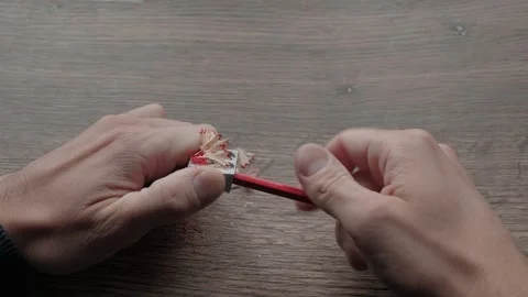 Hands twisting red pencil inside metal sharpener Stock Footage 341365153