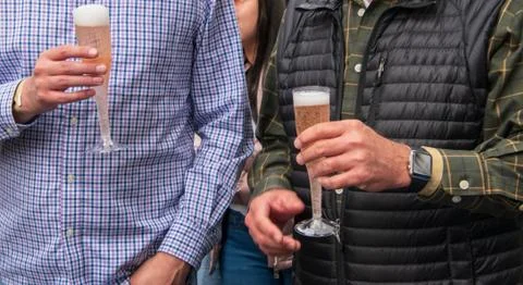 The hands of two caucasian men holding champagne in flutes. Stock Photos