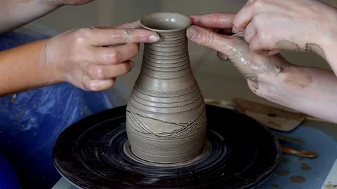 Hands of two people create pot, potter's wheel. Teaching pottery Stock Footage 78142791