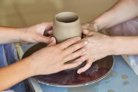 Hands of two people create pot, potter's wheel. Teaching pottery Stock Photos