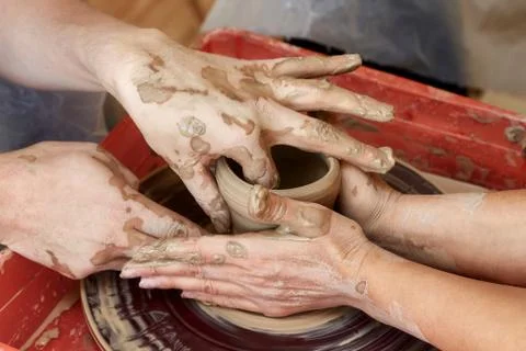Hands of two people create pot, potter's wheel. Teaching pottery Stock Photos