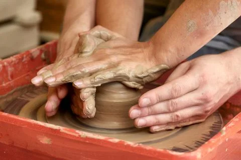 Hands of two people create pot, potter's wheel. Teaching pottery Stock Photos