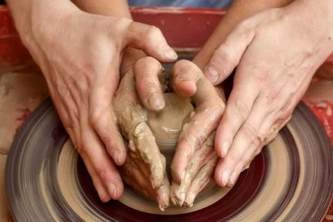 Hands of two people create pot, potter's wheel. Teaching pottery Stock Photos