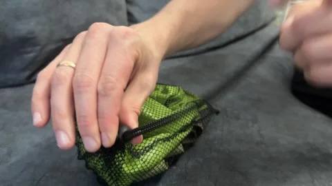 Hands tying a black string on a green mesh produce bag Stock Footage 336524298